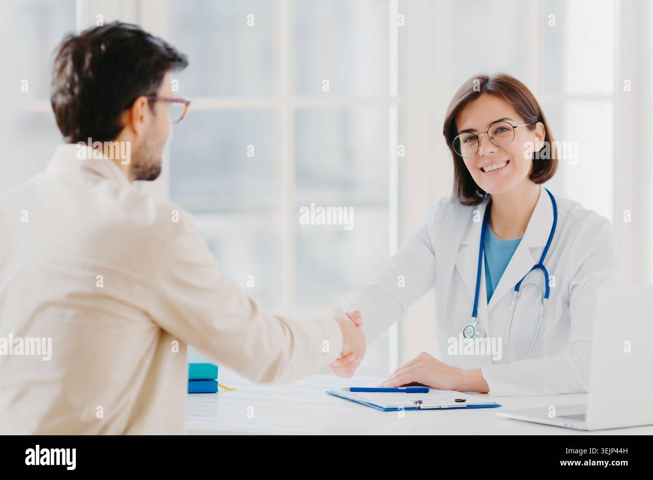 Partnerschaft, Assistenz, Vertrauen und medizinisches Konzept. Frau Ärztin schüttelt Hand mit dankbarem Patienten für gute Behandlung und Pro Stockfoto