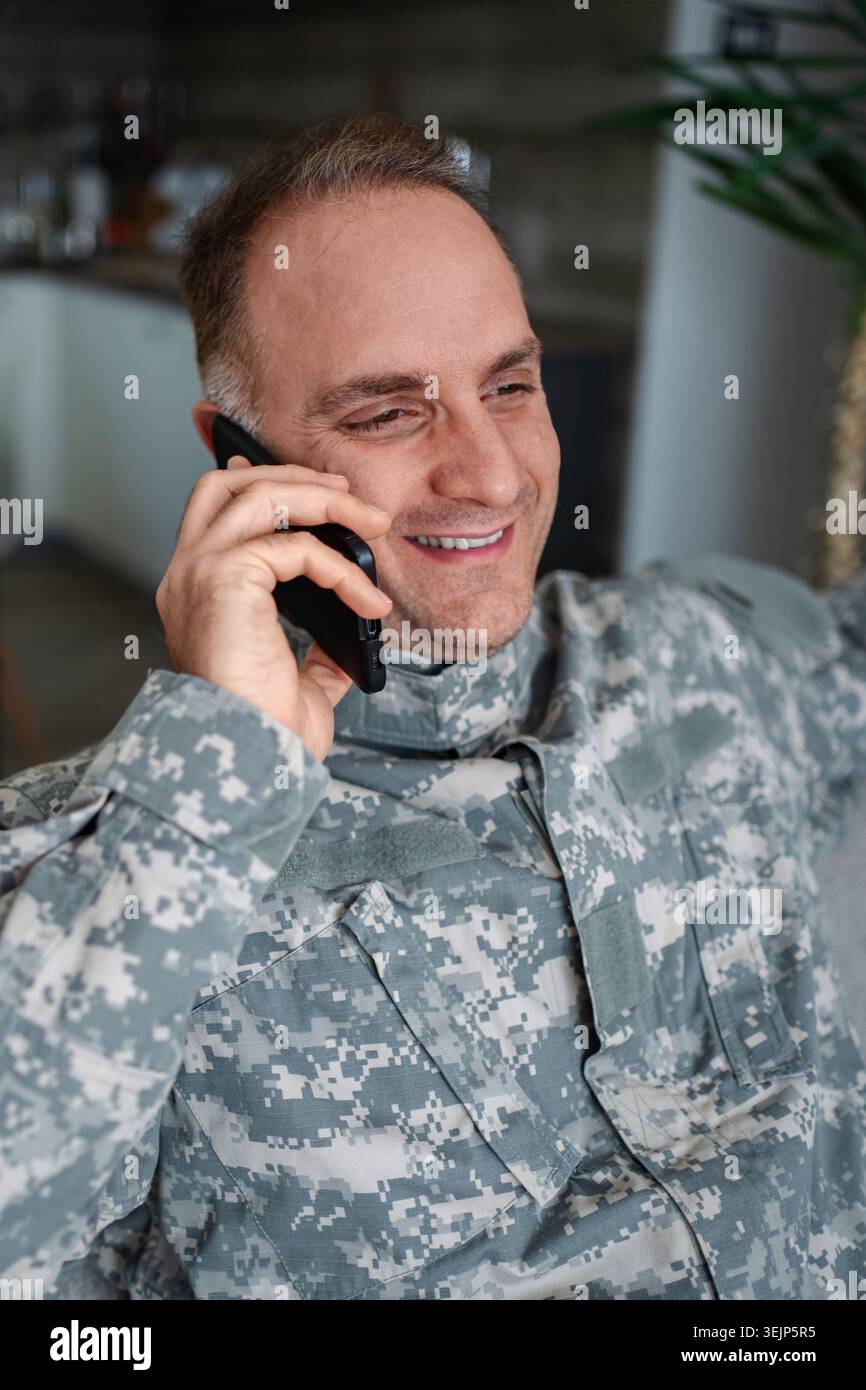 Glücklicher Militärmann, der auf einem Smartphone spricht Stockfoto