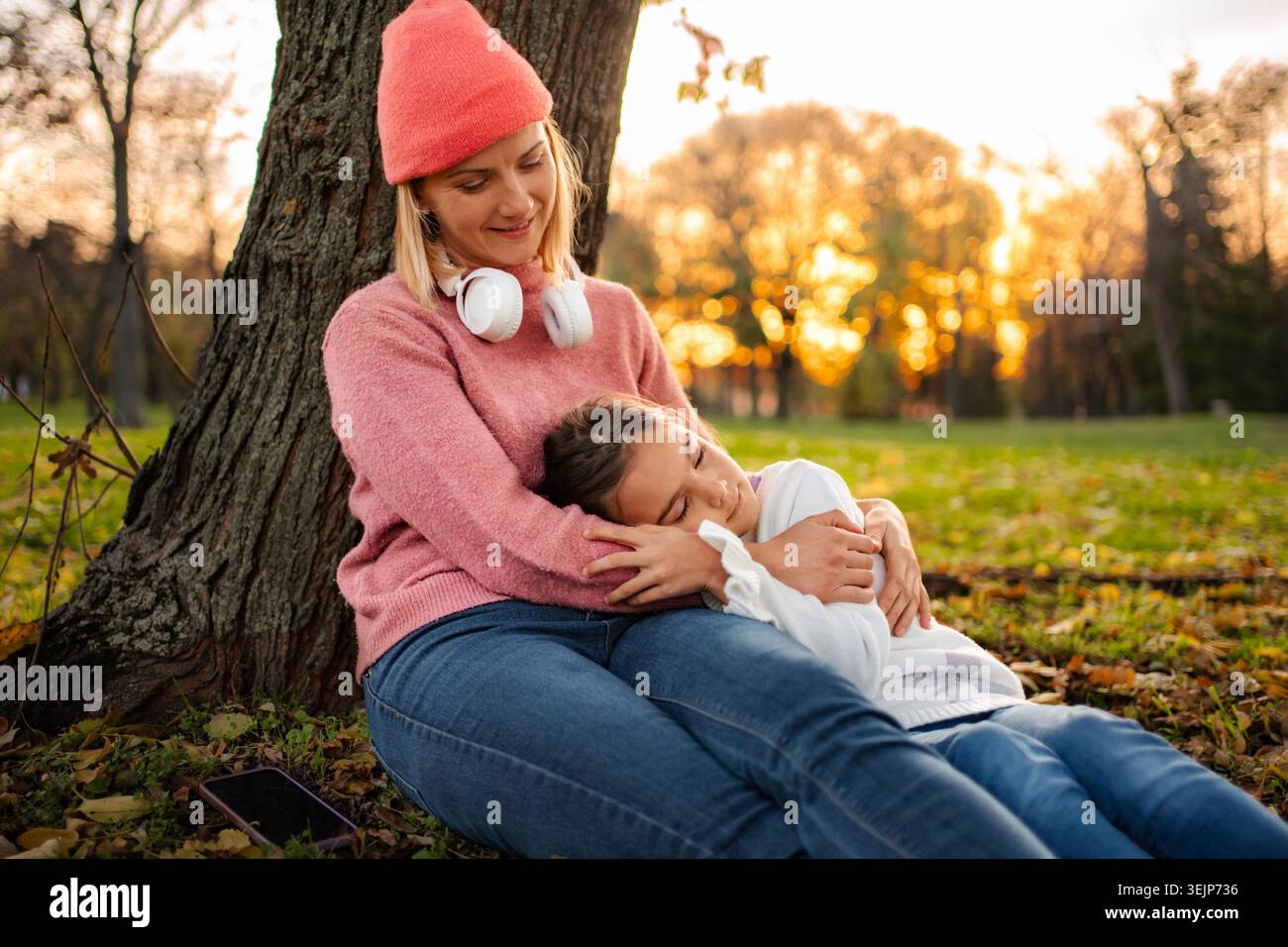 Mutter und Tochter entspannen im Park während des Sonnenuntergangs im Herbst Stockfoto