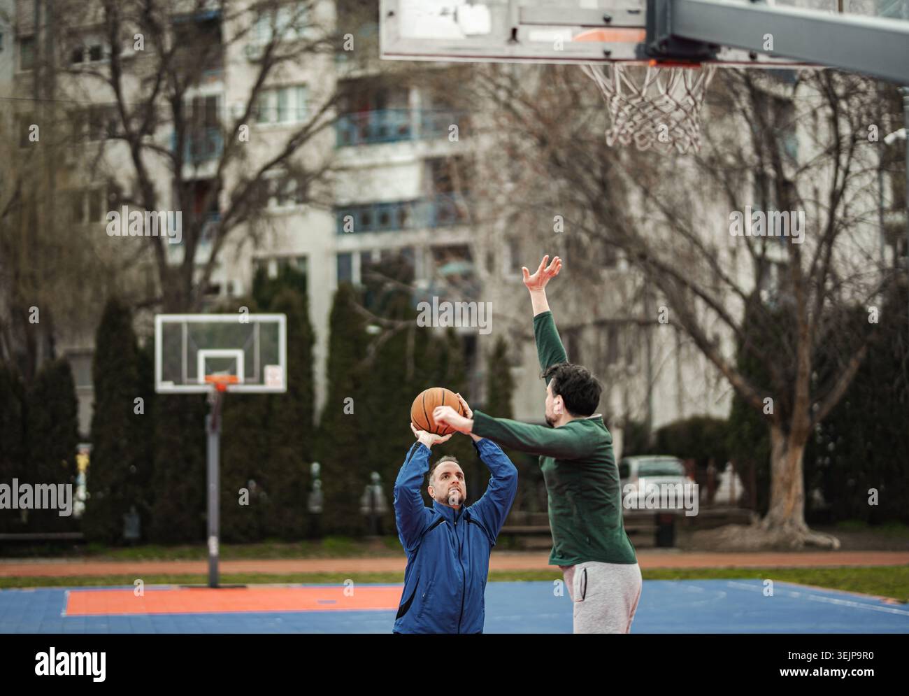 Zwei Männer spielen draußen Basketball und blockieren Schuss Stockfoto