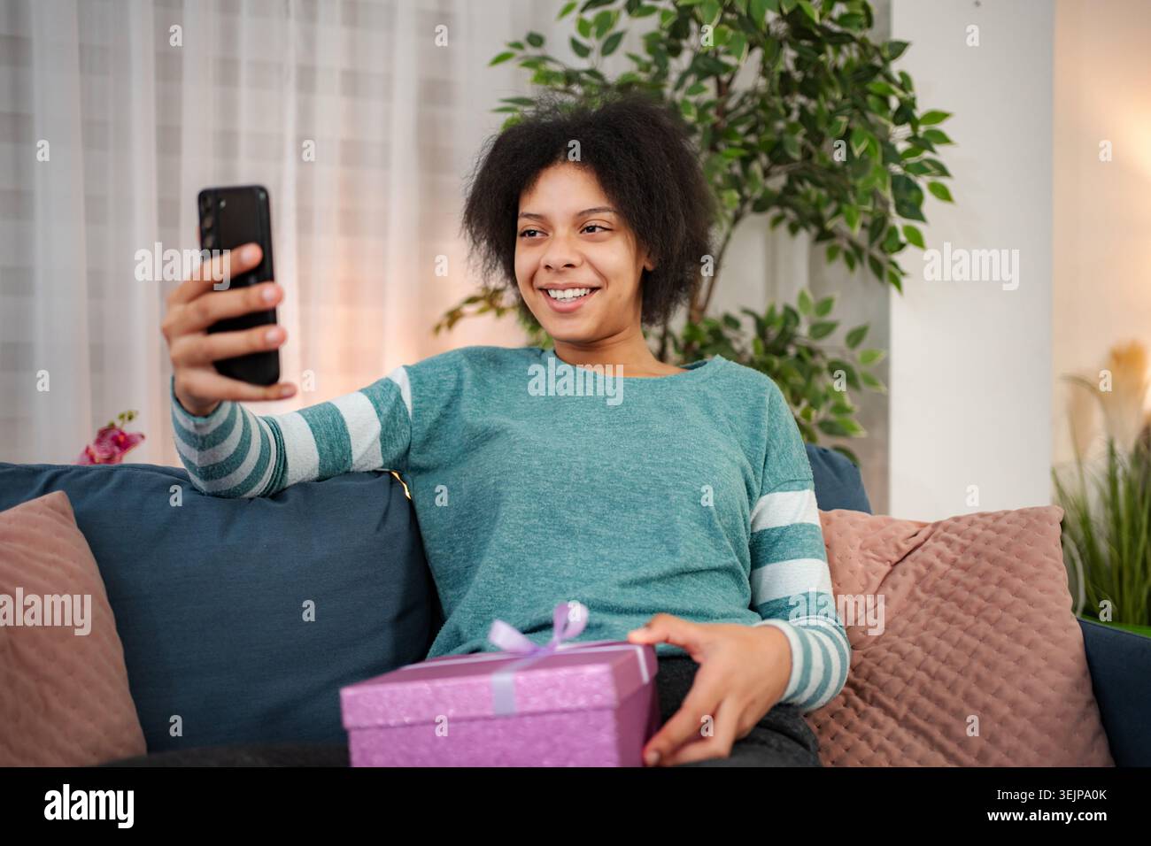 Eine junge Frau, die einen Videoanruf hat, um das Geschenk zu feiern Stockfoto