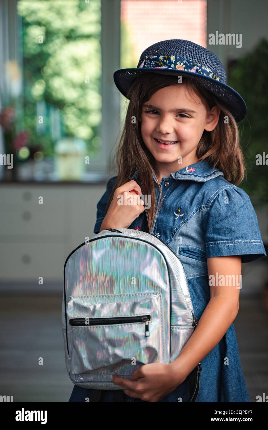 Lächelnde Studentin mit Hut und Rucksack zu Hause Stockfoto