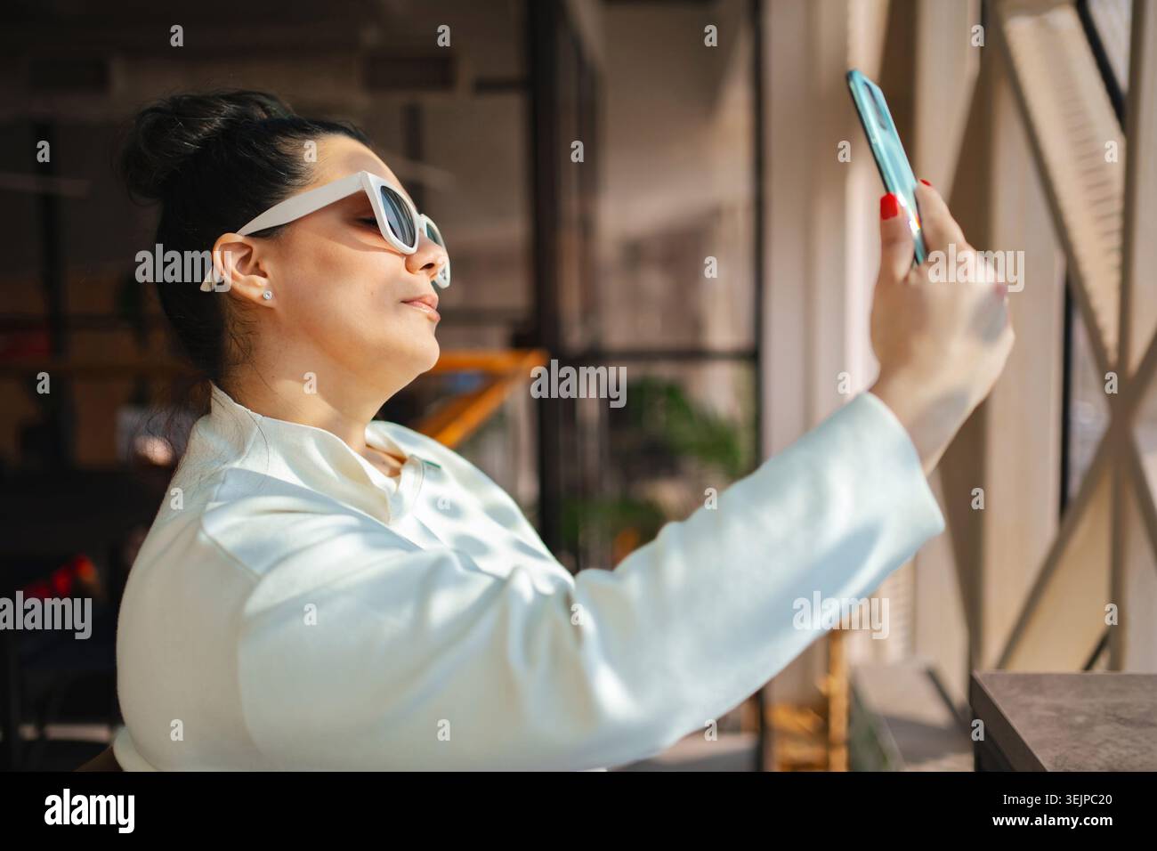 Frau, die einen freudigen Moment festnimmt, während sie drinnen ein Selfie macht Stockfoto