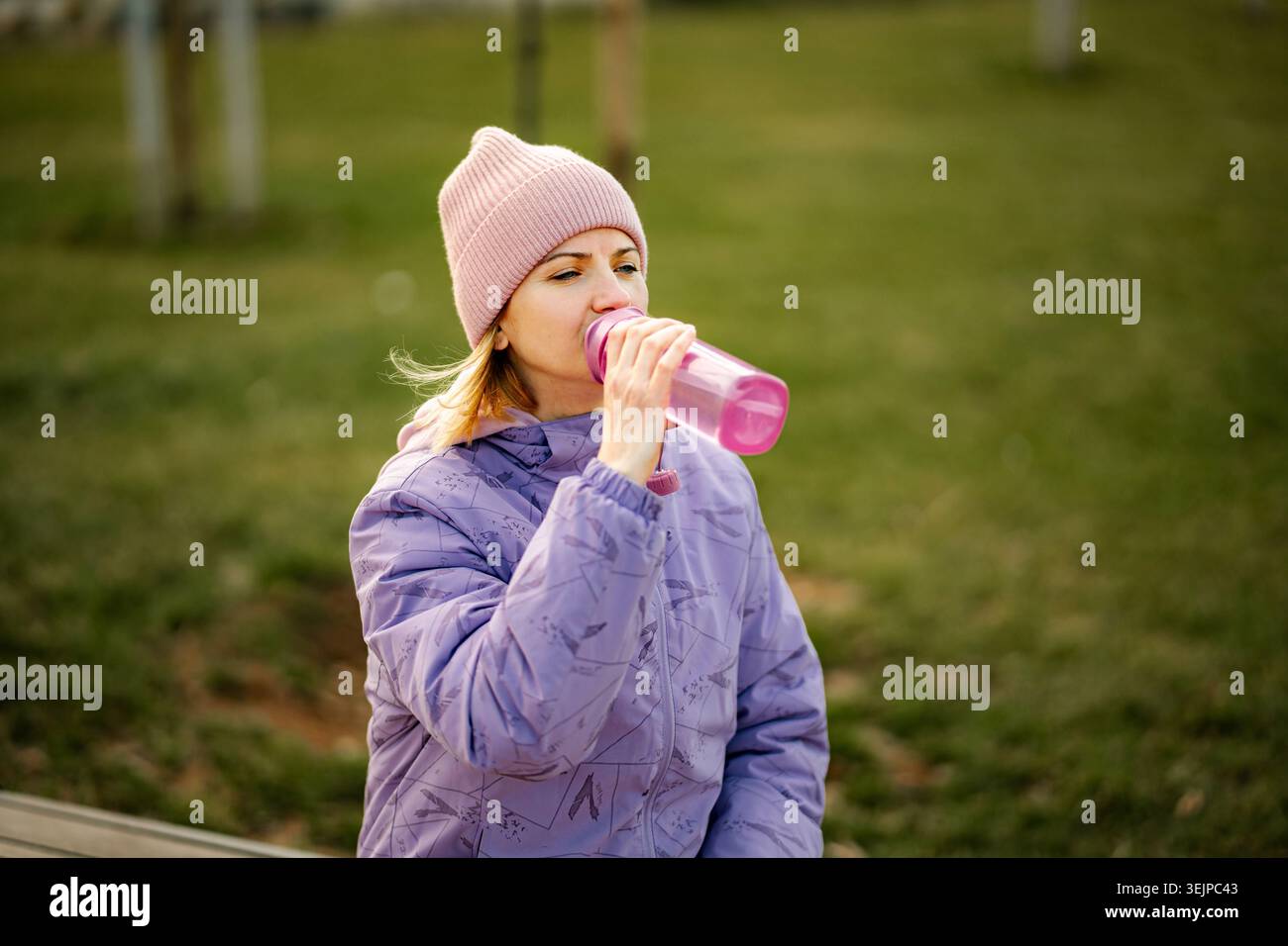 Frau trinkt Wasser aus wiederverwendbarer Flasche im Freien nach dem Training Stockfoto