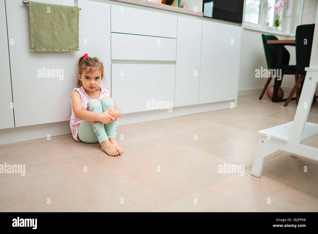 Das Kind sitzt auf dem Boden, in Gedanken verloren Stockfoto