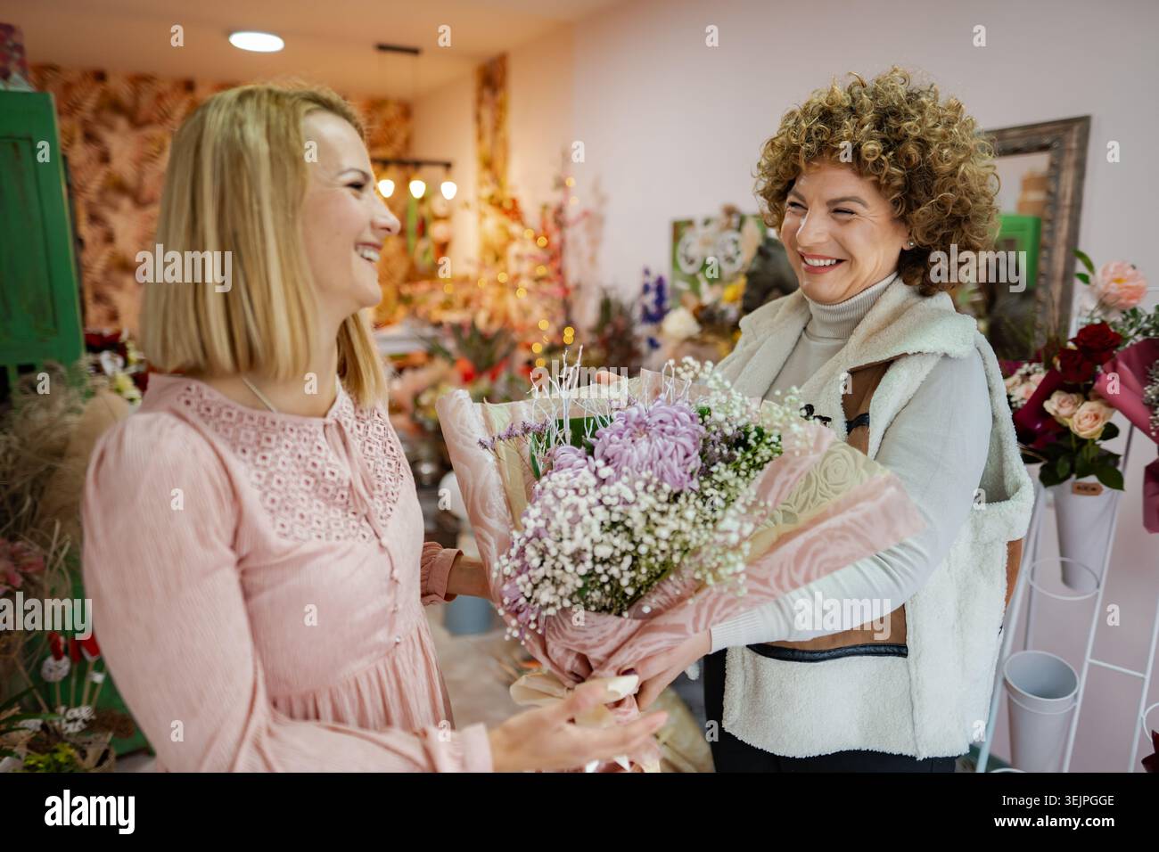Ein freudiger Moment in einem Blumenladen, während zwei Freunde einen besonderen Anlass feiern Stockfoto