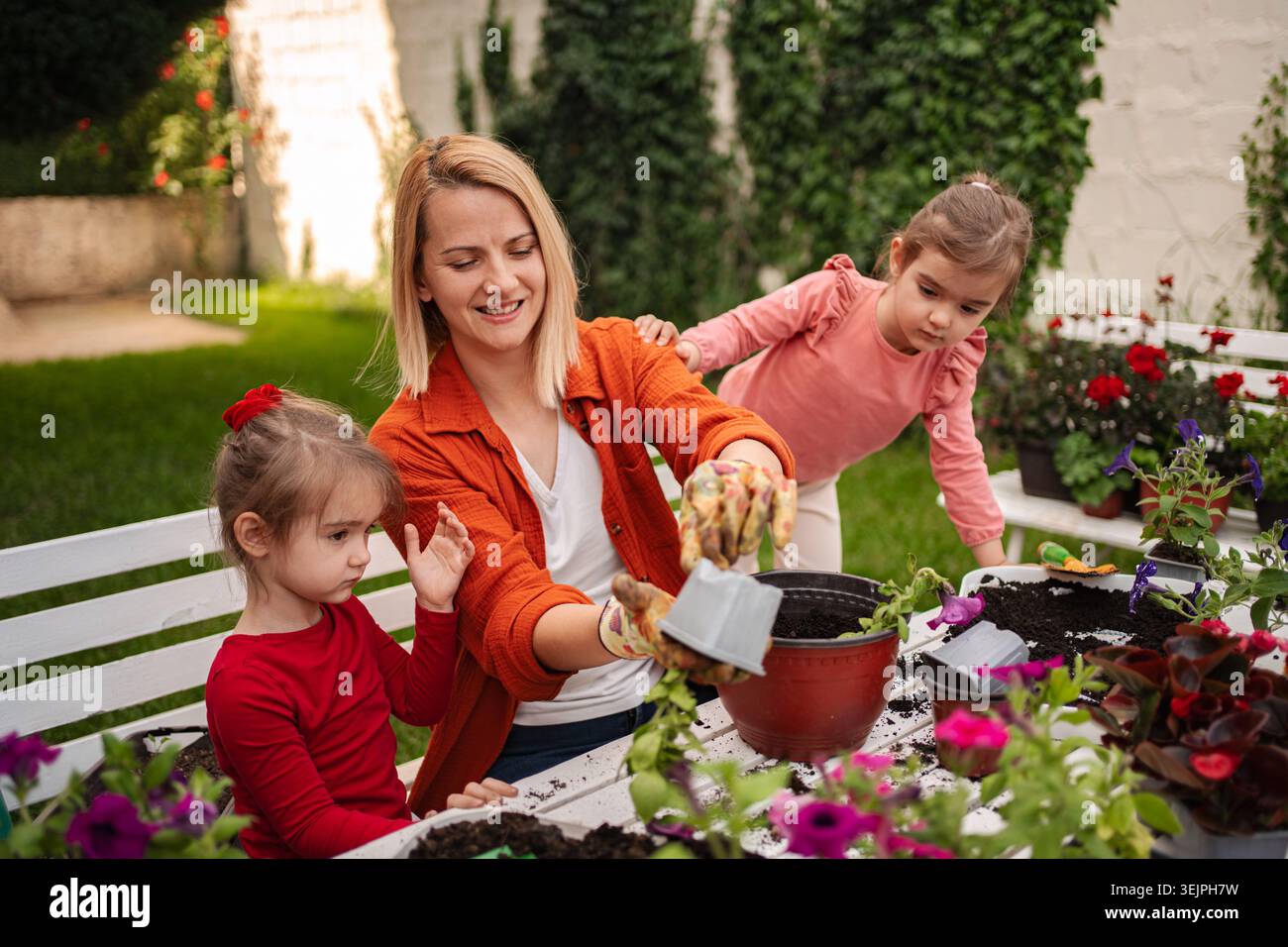 Zwei Kinder Pflanzen fröhlich Blumen mit ihrer Mutter Stockfoto