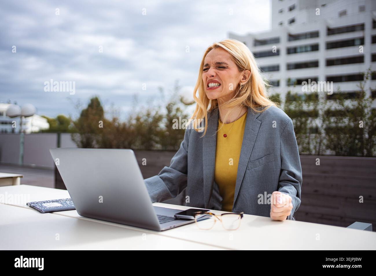Frustrierte junge Frau, die mit der Arbeit am Laptop im Freien zu kämpfen hat Stockfoto