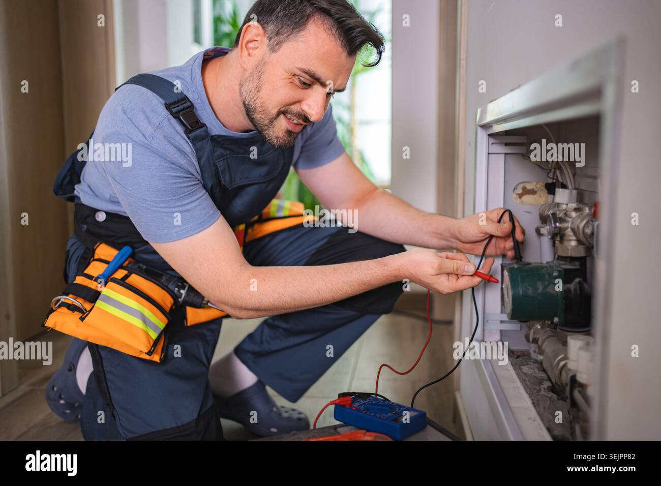 Elektriker, der die Spannung der Heizpumpe im Kesselraum misst Stockfoto