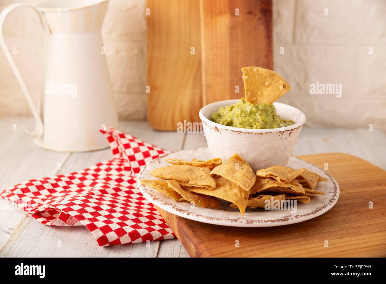 Guacamol. Avocado Dip Sauce, eine der vielen Arten, sie zu konsumieren, wird auf Tortilla Chips, auch Nachos genannt, verteilt. Mexikanisches Rezept für hausgemachte Soßen Stockfoto