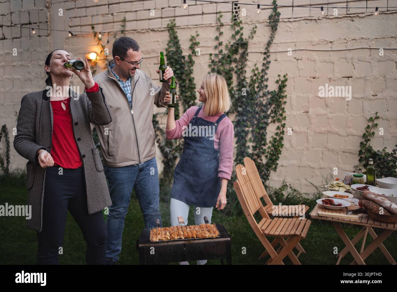 Freunde feiern im Freien mit einem Barbecue und Lachen im Abendglühen Stockfoto