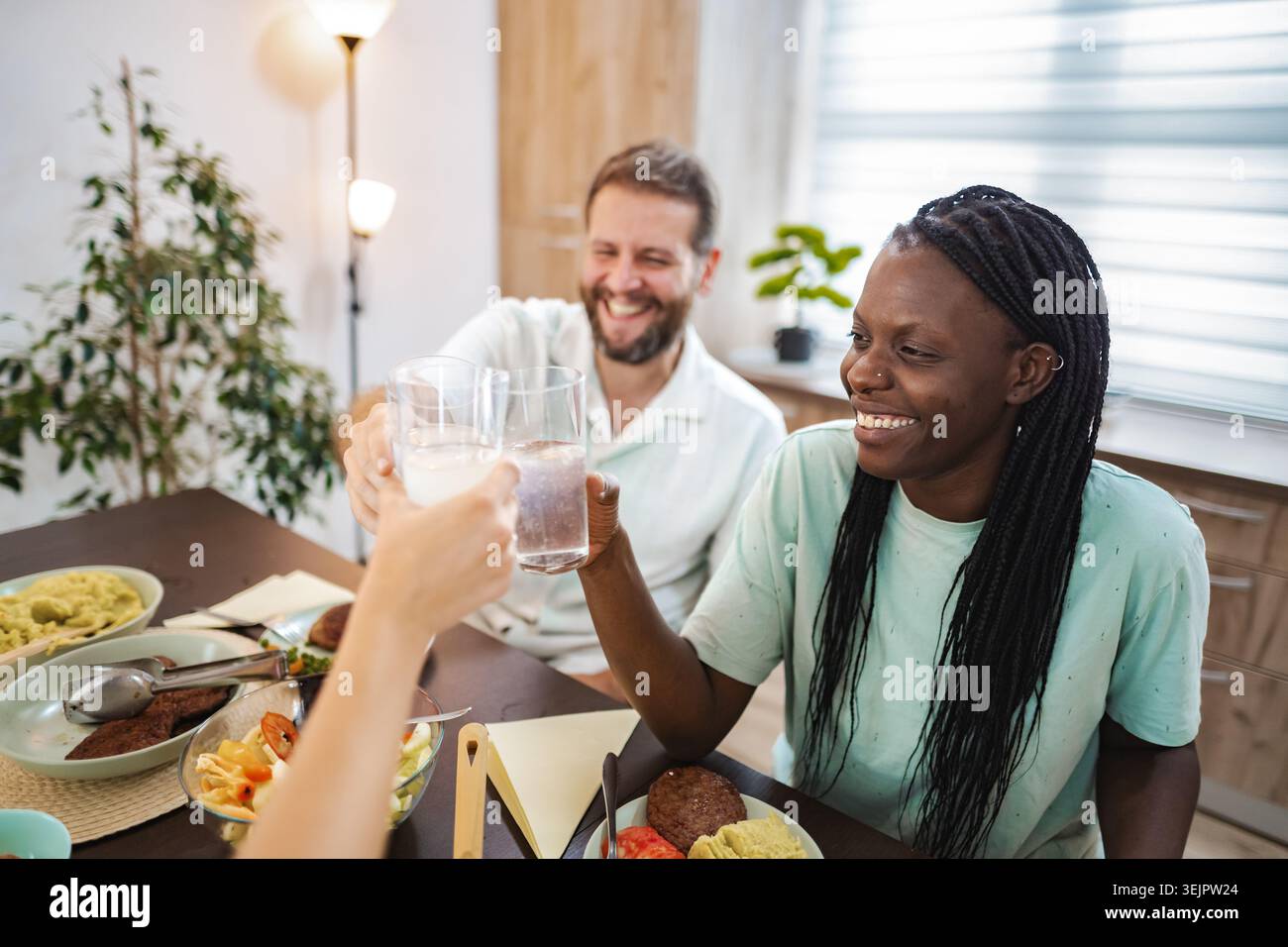 Freunde, die in einem gemütlichen Speisesaal eine fröhliche Mahlzeit genießen Stockfoto