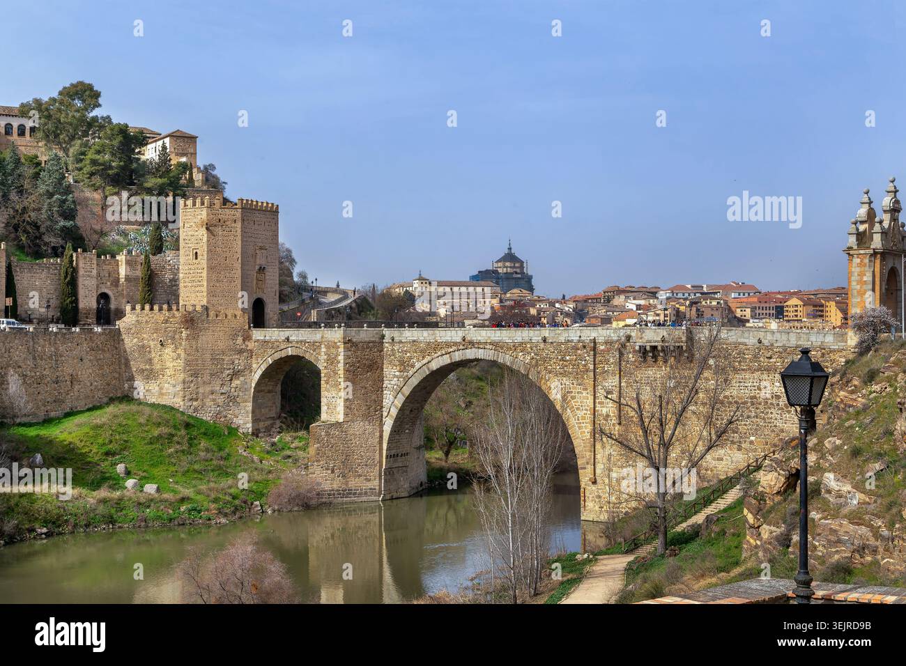 Puente de Alcantara römische Bogenbrücke über den Fluss Tejo in Toledo, Spanien. Historische Steinbefestigung bei hellem Tageslicht Stockfoto