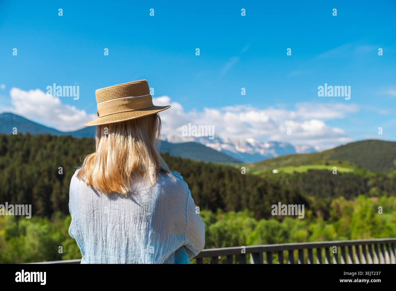 Junge Frau mit Strohhut, die einen Panoramablick auf die katalanischen Pyrenäen genießt Stockfoto