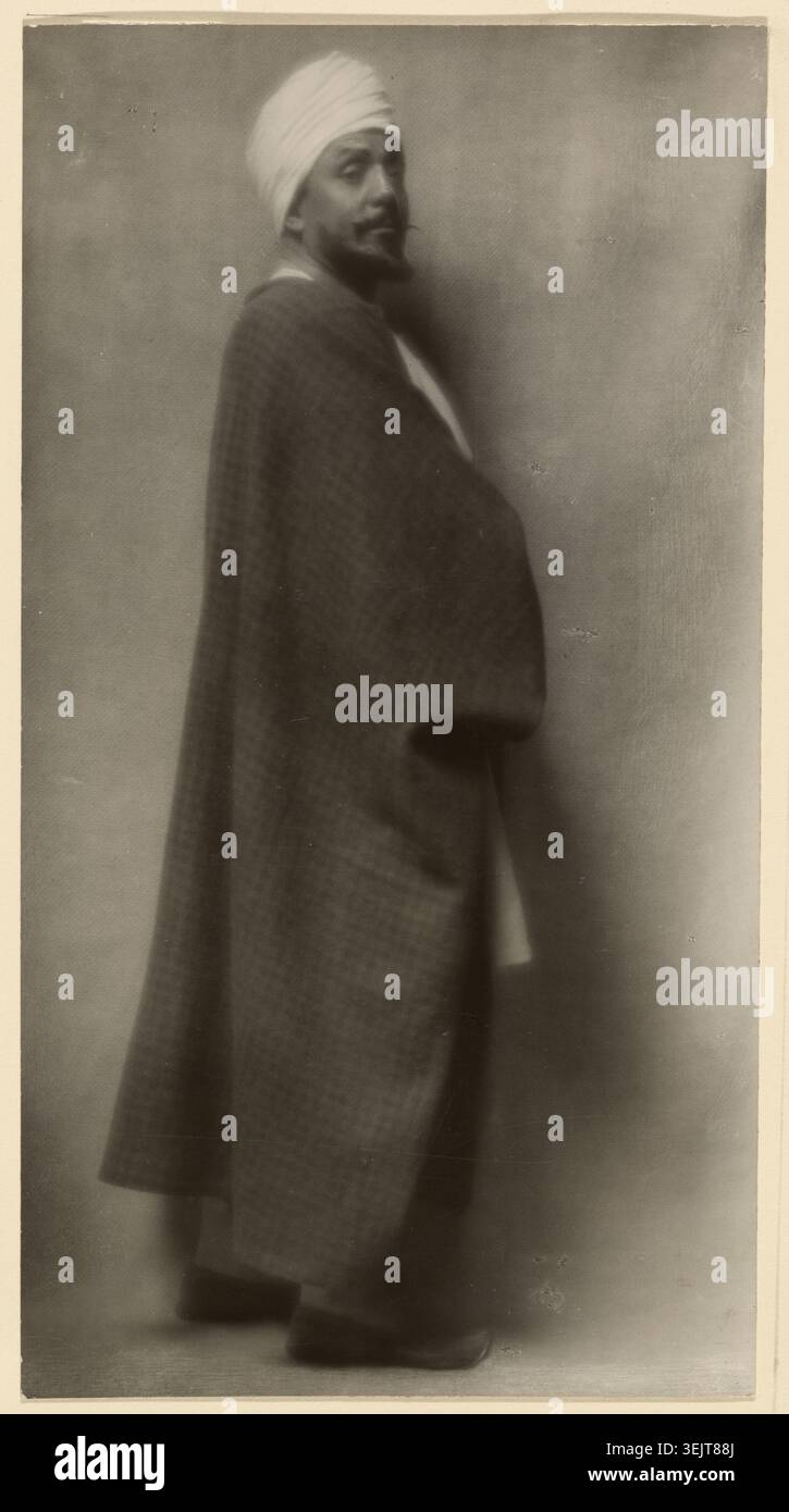Otis Skinner (in Kismet), 1912. Zusätzliche Informationen: Porträt von Otis Skinner in voller Länge mit Spitzbart, erhöhter Augenbraue und weißem Turban, der über seine rechte Schulter auf den Betrachter blickt und lose, formlose Kleidungsstücke trägt. Stockfoto