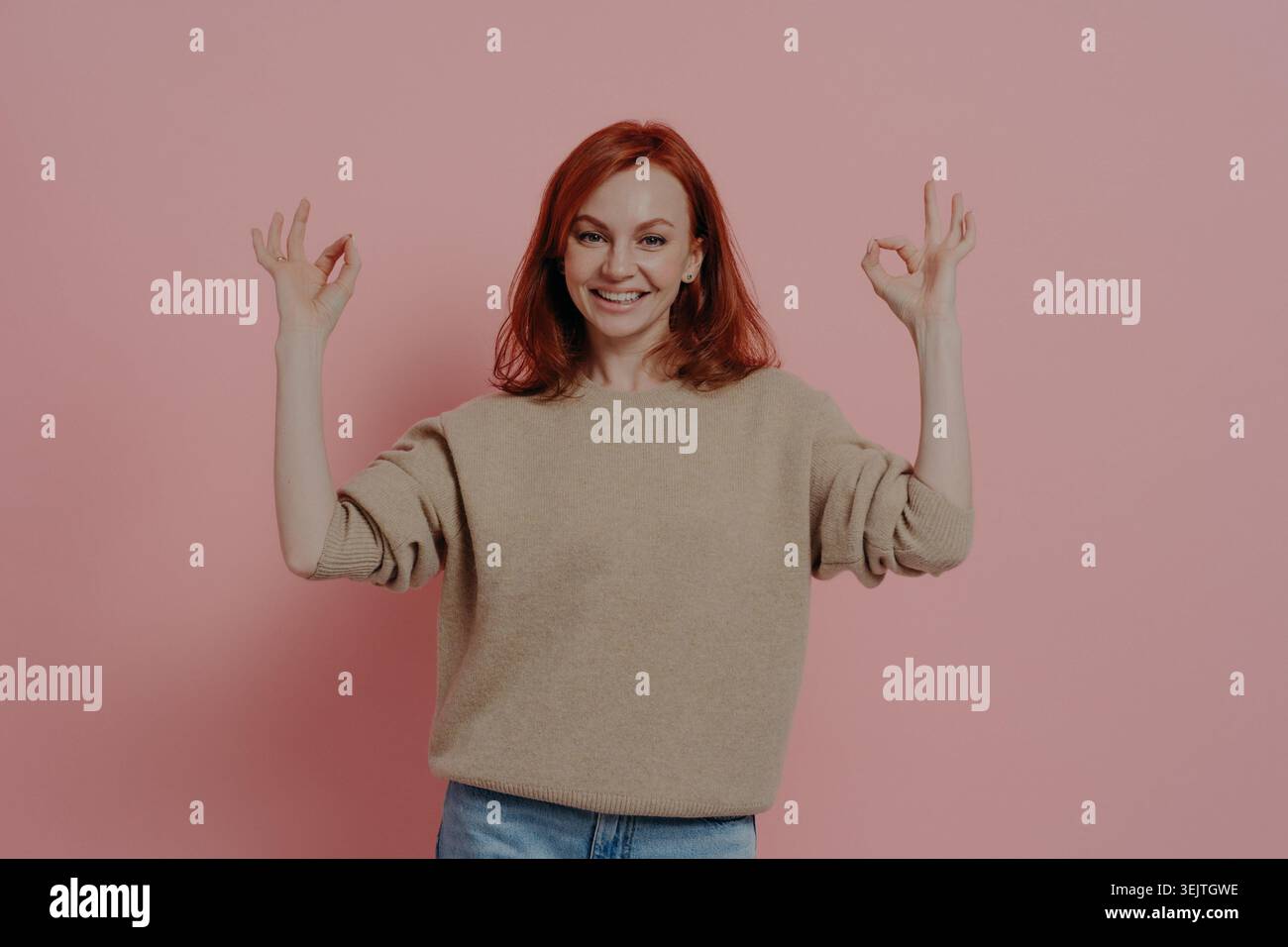Halblanges Bild einer hübschen Ginger-Frau, die mit beiden Händen OK-Zeichen zeigt, dass alles in Ordnung ist, in lässigem Outfit gekleidet, zufriedenes rothaariges Model, das isoliert über rosa Hintergrund posiert Stockfoto