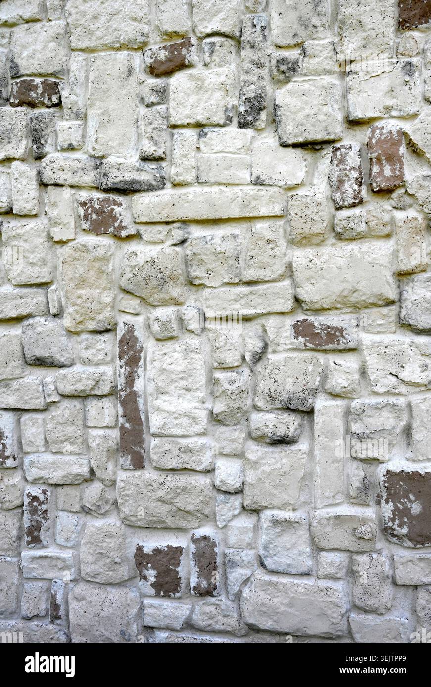 Stein- und Mörtelwandoberfläche mit hellgrauen, braunen und dunkleren, porösen Gesteinen unterschiedlicher Größe, rauen, unebenen Texturen, glatten, unebenen Mörtelfugen Stockfoto