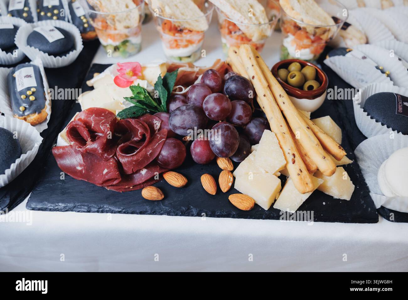 Käseplatte mit verschiedenen Aufschnitten, Trauben, Mandeln und Brotstäbchen Stockfoto