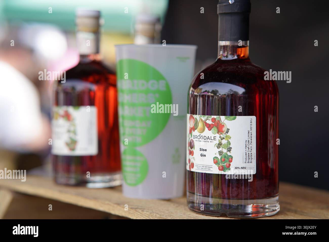 Helmsdale Sloe Gin-Flaschen werden auf Holztisch beim sonnigen Sommerfest im Freien oder am Farmers Market Stand ausgestellt. Tonbridge, Food and Drink Festival Stockfoto