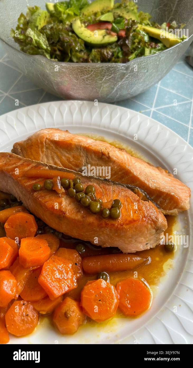 Lachs mit gedünsteten Karotten und einer Schüssel Salat Stockfoto