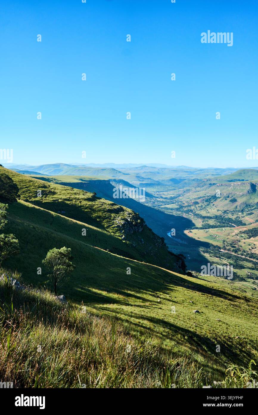 Riesiges, grünes Tal unter klarem azurblauen Himmel mit weit entfernten Bergrücken Stockfoto