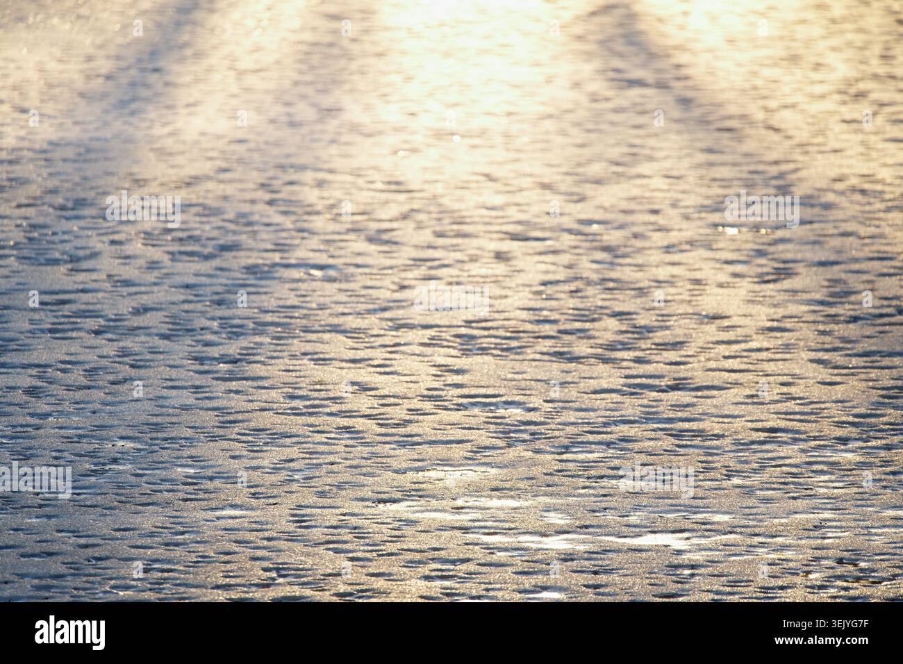 Gefrorenes Seewasser mit weichen Wellen, die Sonnenlicht reflektieren. Horizontales Foto Stockfoto