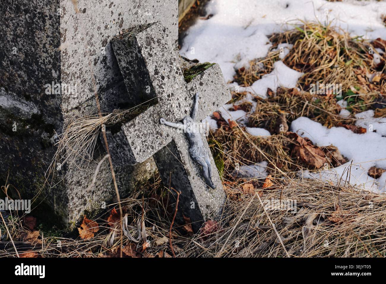 Altes Kreuz und Grab auf dem ländlichen Friedhof. Erinnerung, Erbe und Tradition im Freien im Winter. Stockfoto