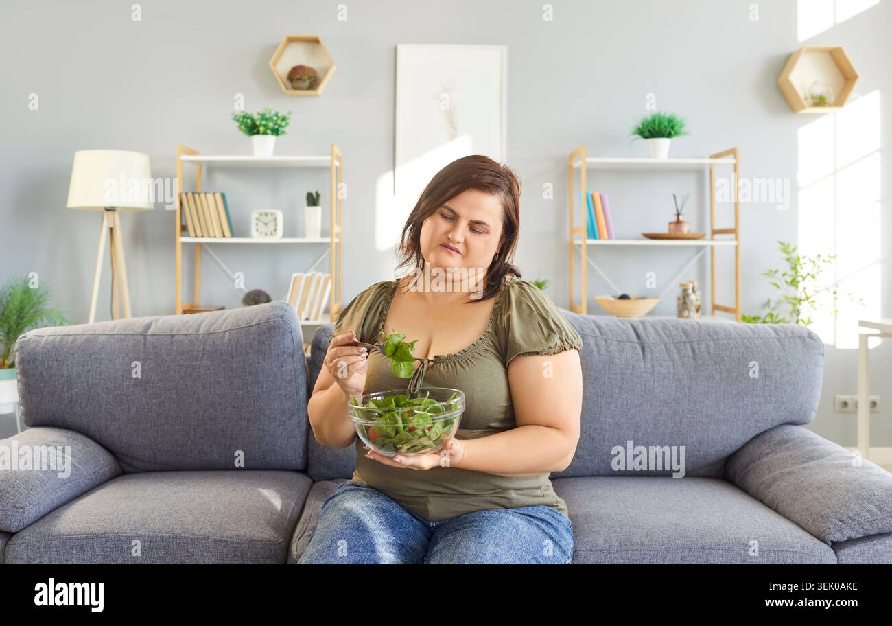 Unglückliche Frau, die traurig ist, vegetarische Diät zu nehmen, grünes Gemüse zu essen, vegetarische Salatkarte Stockfoto
