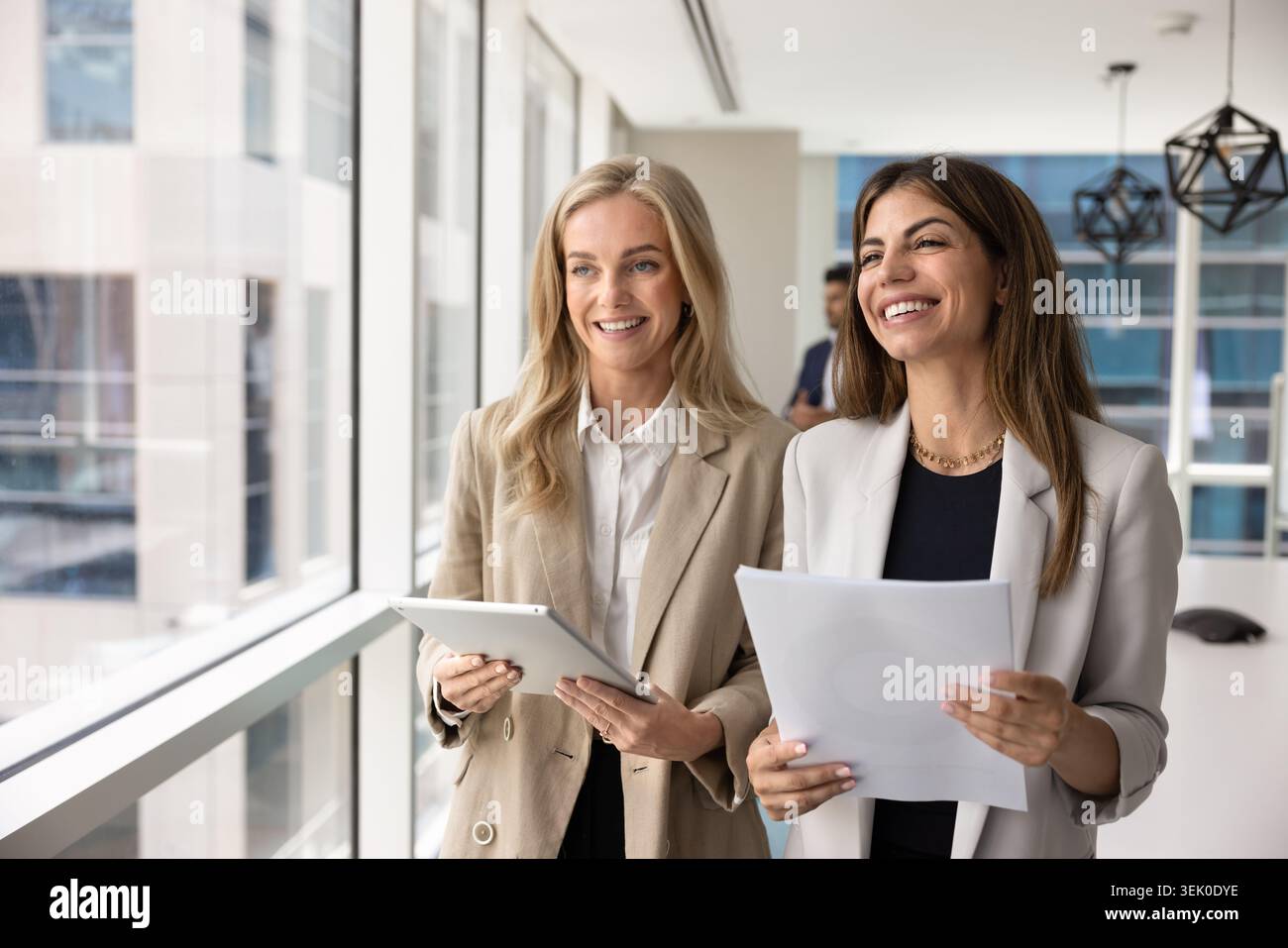 Frauen, die Dokumente und Tablets zusammen halten, stehen in modernen Sitzungsräumen Stockfoto