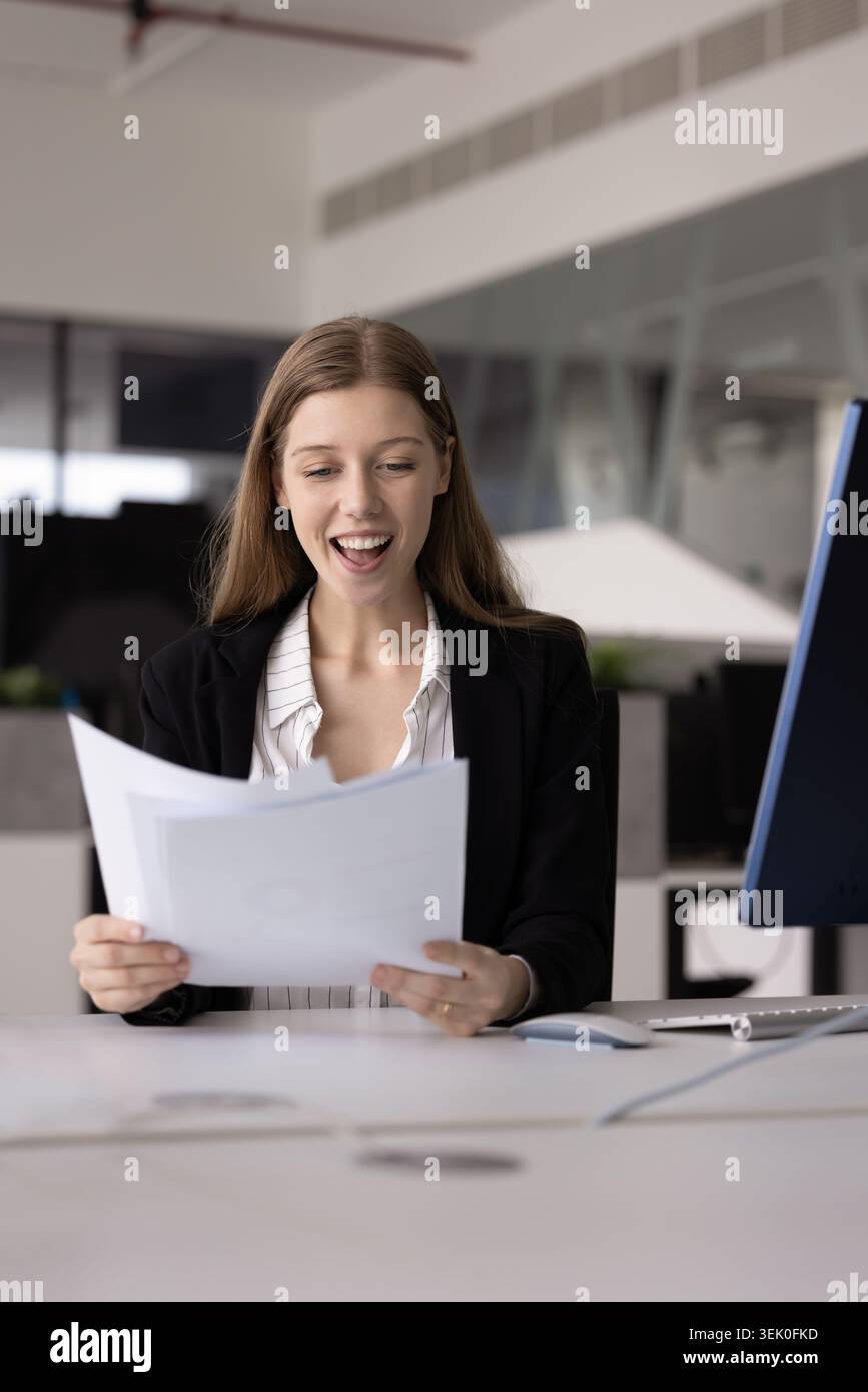 Geschäftsfrau fühlt sich beim Lesen von Dokumenten angenehm überrascht oder aufgeregt Stockfoto