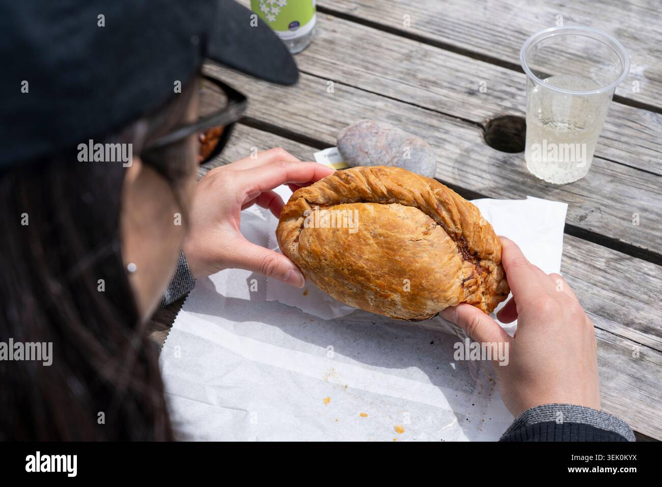 Frau, die ein traditionelles Steak mit Cornish Pasty hält, ein gebackenes Gebäck gefüllt mit Rindfleischwürfeln, Kartoffeln, Swede & Zwiebeln, Kynance Cove, Cornwall, UK Stockfoto