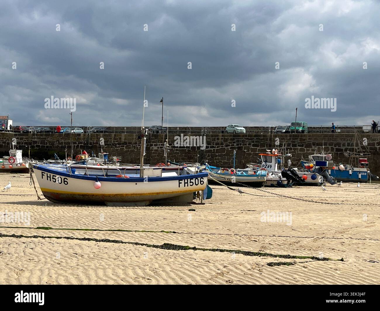 Boote am Harbour Beach mit Smeaton's Pier im Hintergrund in St Ives, Cornwall, England, UK. - Smartphone-aufgenommenes Stockfoto