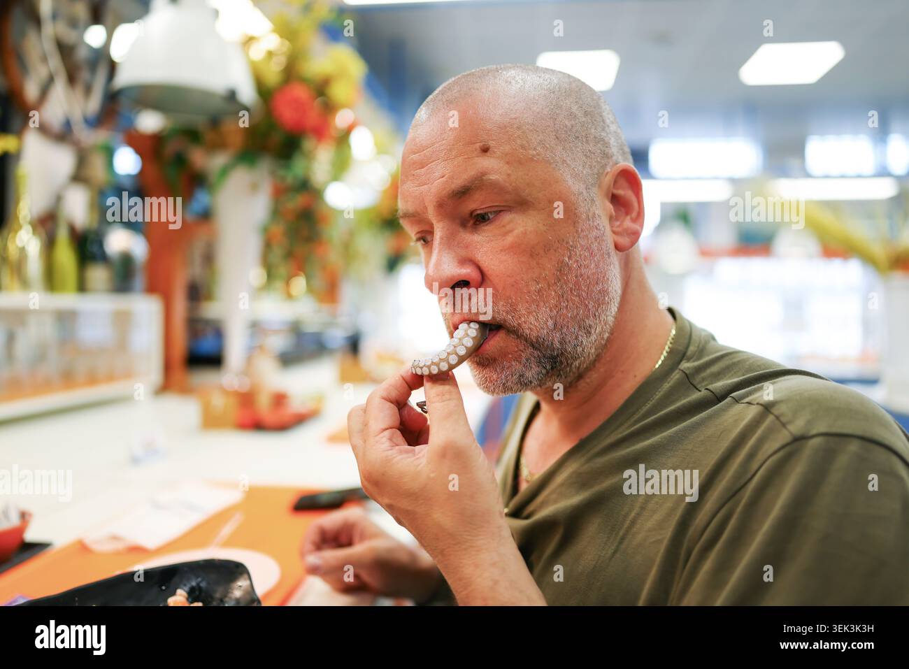 Touristen probieren exotische Meeresfrüchte-Snacks auf dem modernen Lebensmittelmarkt, lässiges Lifestyle-Porträt mit frischen Tintenfischen und Garnelen auf Eis. Stockfoto