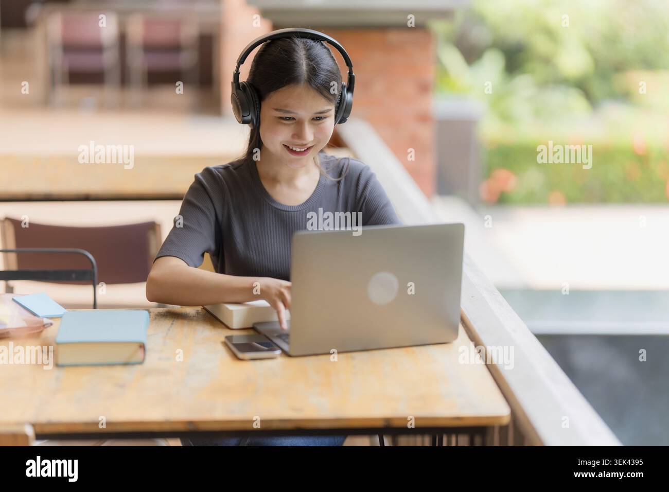 Junge asiatische Studentin liest Bücher in der Bibliothek Stockfoto