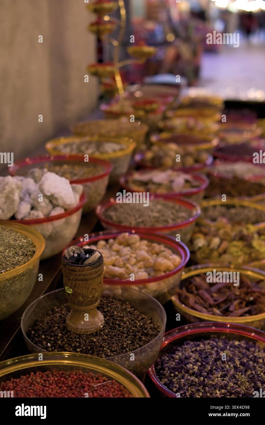 Burning Oud Weihrauch in Holz Bakhoor Burner umgeben von Gewürzen Weihrauch Display mit aromatischen Kräutern in Marktschalen im Souk Al Seef Dubai Stockfoto