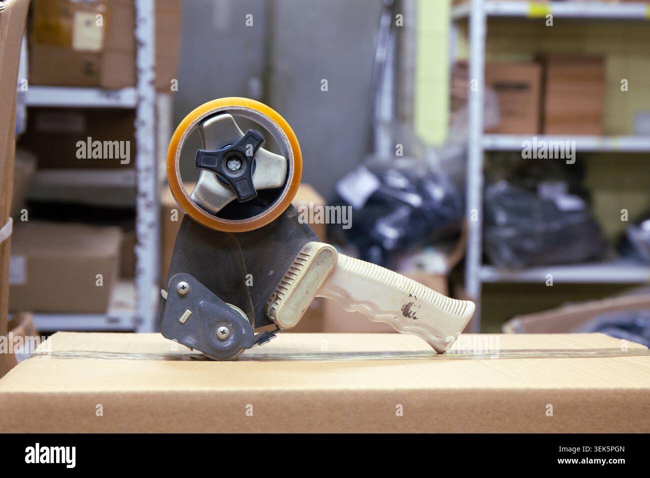 Verpackungsband-Spender mit Rollenband auf Karton aus nächster Nähe Stockfoto