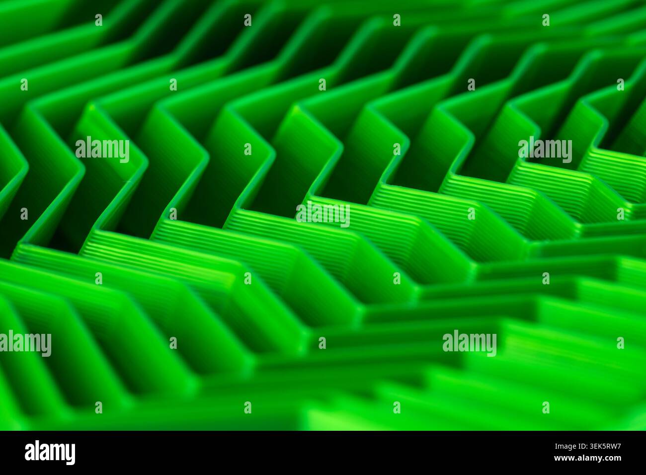 Makroansicht hellgrüner, strukturierter Chevron-Linien, die einen futuristischen abstrakten Hintergrund schaffen Stockfoto