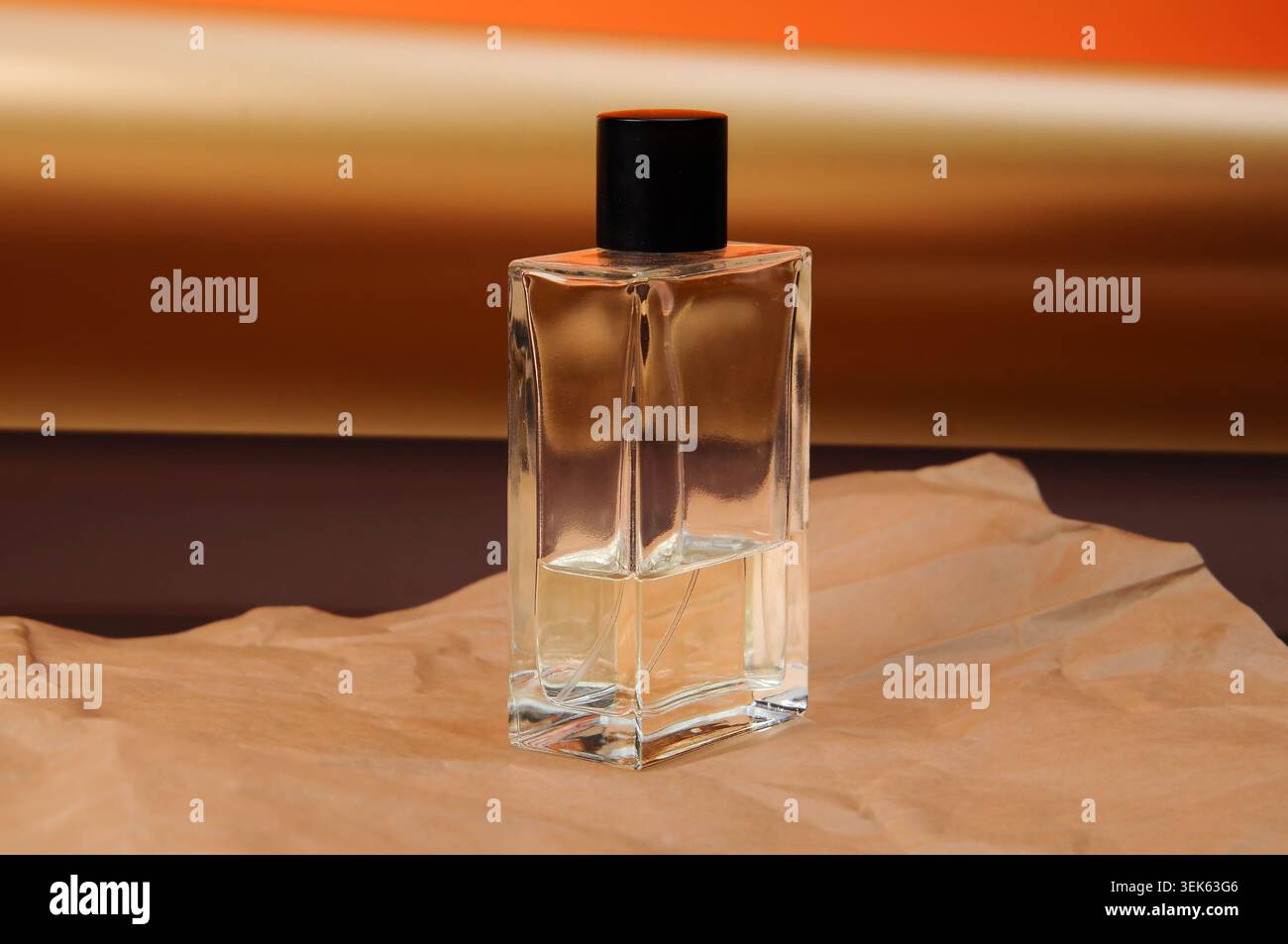 Elegante Glasparfümflasche mit schwarzem Verschluss auf strukturiertem Papierhintergrund Stockfoto