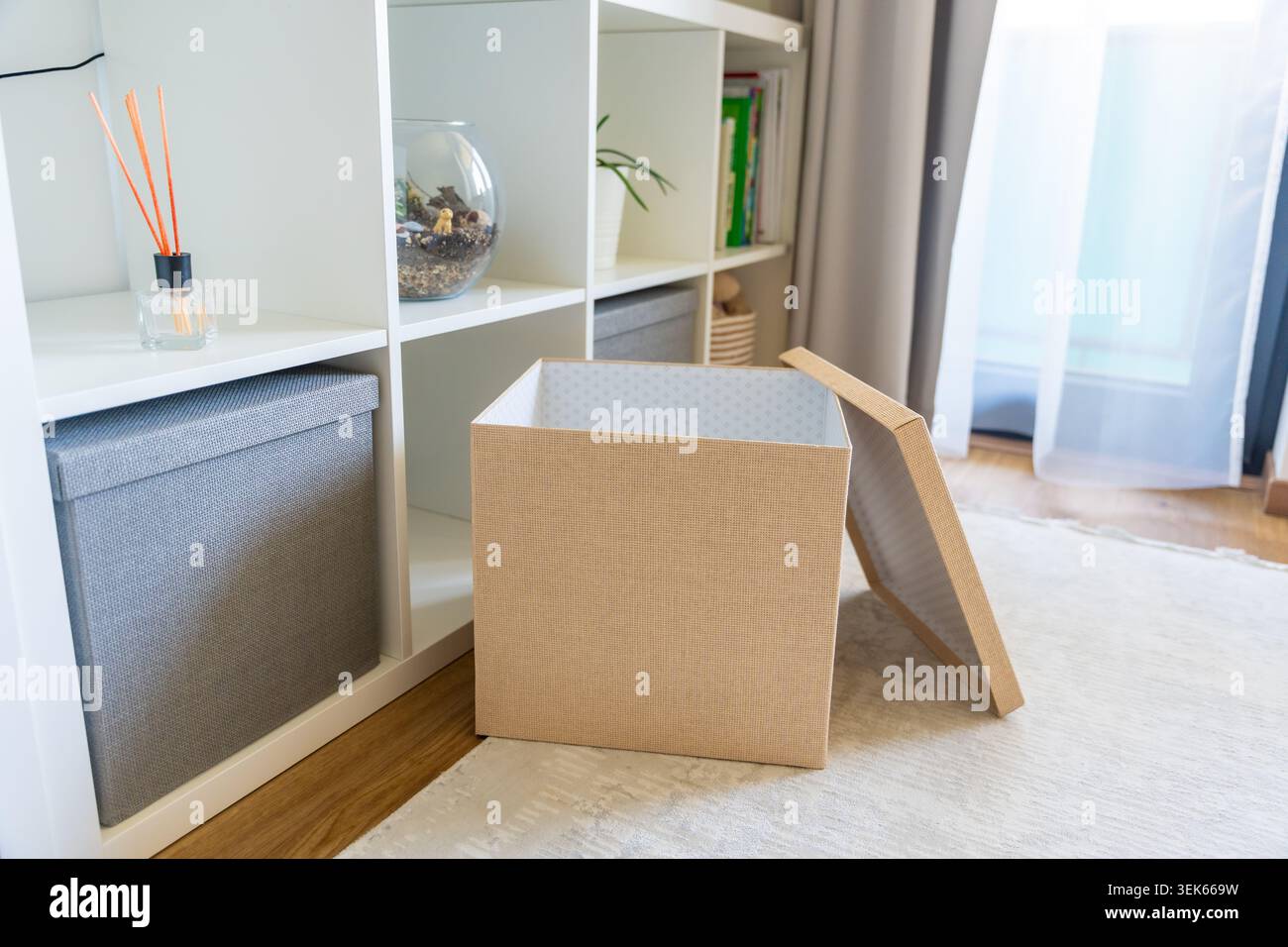 Öffnen Sie die Aufbewahrungsbox in der Nähe des Regalsystems im organisierten Innenraum. Heimorganisation und Entklammerung des Lebensstils Stockfoto