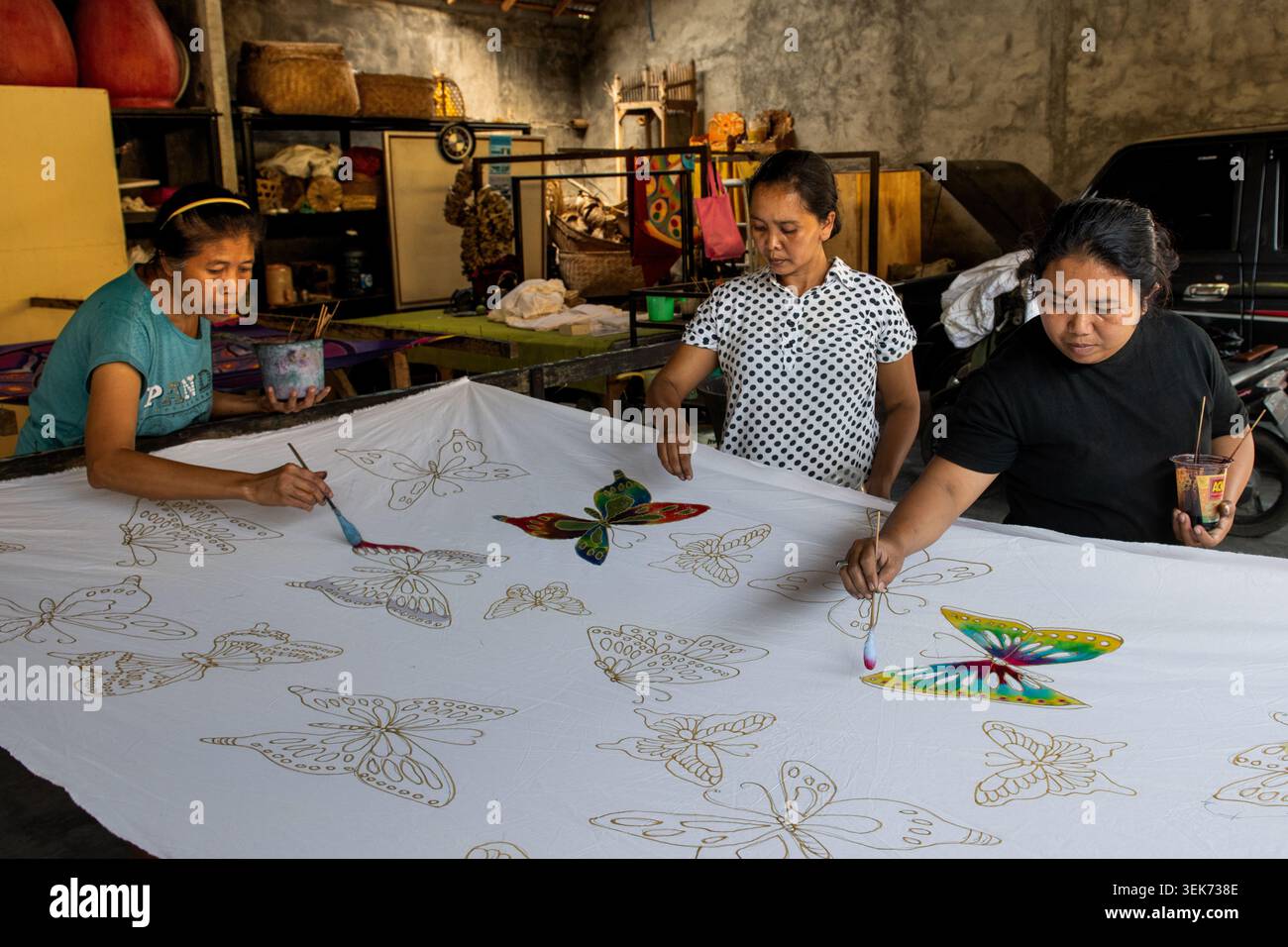 Bali, Indonesien, 28. Oktober 2019: Arbeiter einer Batikdruckerei auf der indonesischen Insel Bali tragen Farbe auf ein weißes Tuch mit Muster auf Stockfoto