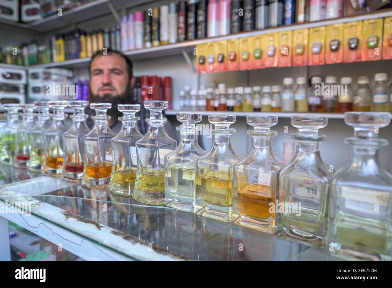Mann auf einem afghanischen Basar, der viele Flaschen mit Duftstoffen und ätherischen Ölen anbietet Stockfoto