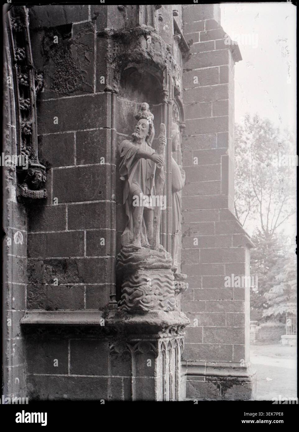 Auf einem Pressefoto ist die Statue des Heiligen Christophorus auf der Apostelhalle der Basilika Notre-Dame du Folgoët aus dem Jahr 1939 dokumentiert. Das Bild dokumentiert eine religiöse Skulptur, die in den architektonischen Rahmen der Basilika in Finistère integriert ist. Stockfoto