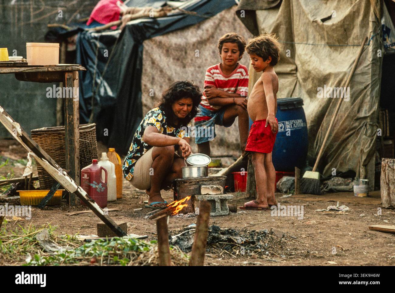 Sao Paolo, Brasilien, 1991: Eine Mutter bereitet Nahrung für ihre Kinder in ihrem temporären Haus auf besetztem Land bei dieser Landinvasion zu. Sie wurden kurz darauf vertrieben. Stockfoto