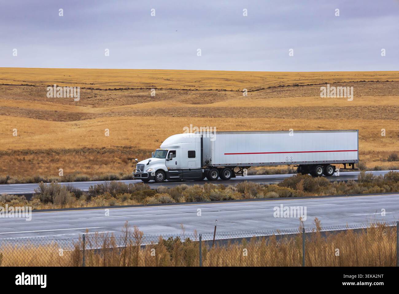 Semi-Truck, der Fracht über eine trockene Wüstenlandschaft auf einer interstate Highway transportiert Stockfoto