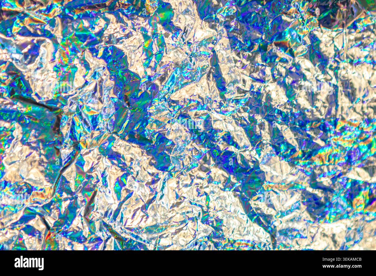 Holographische, zerknitterte Folie mit schillerndem Regenbogenglanz und metallischer Textur für Hintergründe Stockfoto