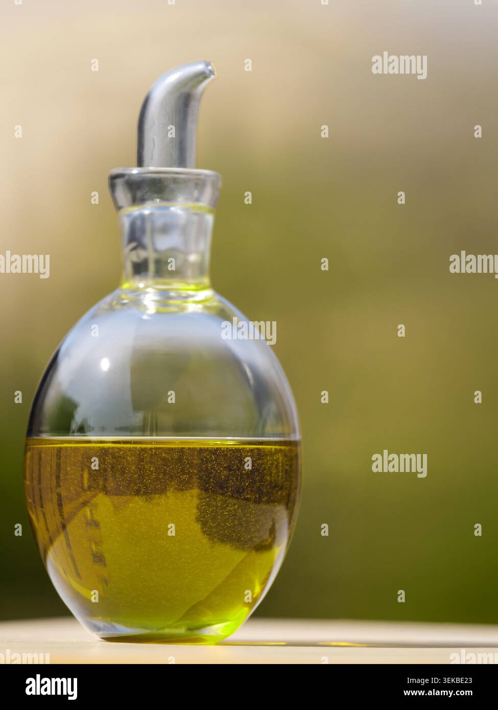 Glas-Olivenölflasche mit verschwommenem natürlichem Hintergrund Stockfoto