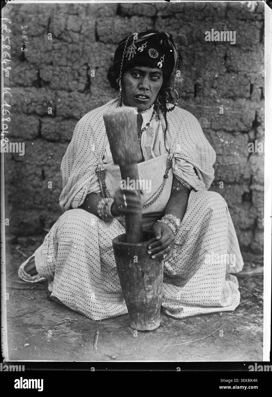 Eine algerische Frau mahlt 1920 in einer traditionellen Holzmühle Getreide. Agence Rol dokumentierte diesen Brauch für die Zubereitung von Lebensmitteln als Teil der Presseberichterstattung über das lokale Leben in Algerien. Stockfoto