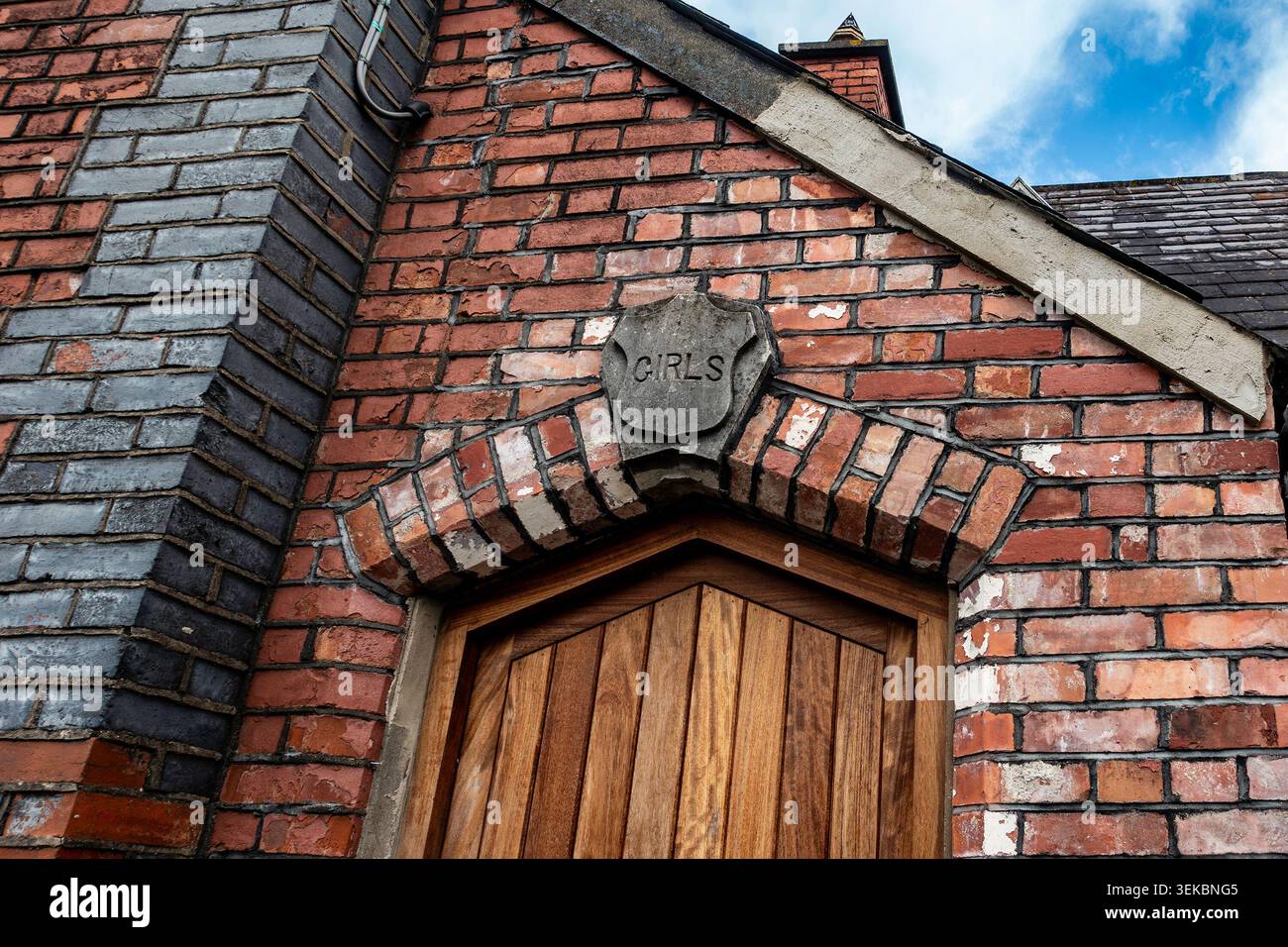 Eingang der alten Schule in Donacarney, County Meath, Irland, mit einer Holztür unter einem Backsteinbogen, auf der eine Steintafel mit MÄDCHEN gemeißelt ist. Stockfoto