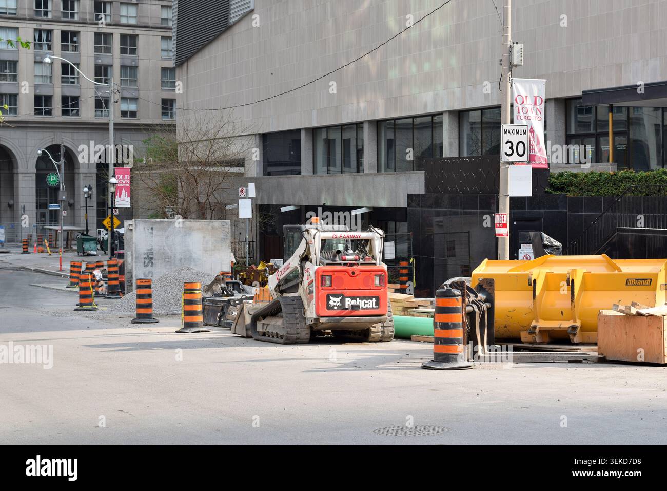 Toronto, Ontario, Kanada - 17. Mai 2026: Städtische Straßenbaustelle in der Innenstadt von Toronto mit Kompaktkettenlader, Verkehrsfässern, Bauwerk Stockfoto
