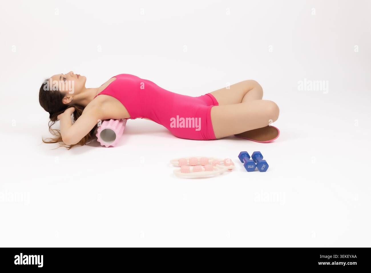 Fitness-Frau, die auf dem Boden liegt und sich mit einer Schaumrolle zurückspannt Stockfoto